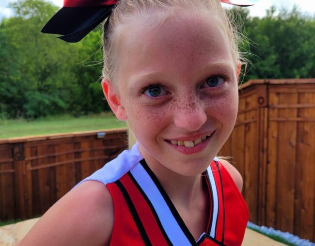 FiFi smiling in her red and black cheerleading uniform