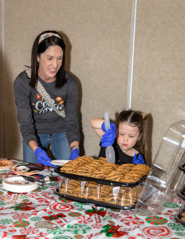 Volunteers serving trays of cookies at the holiday party