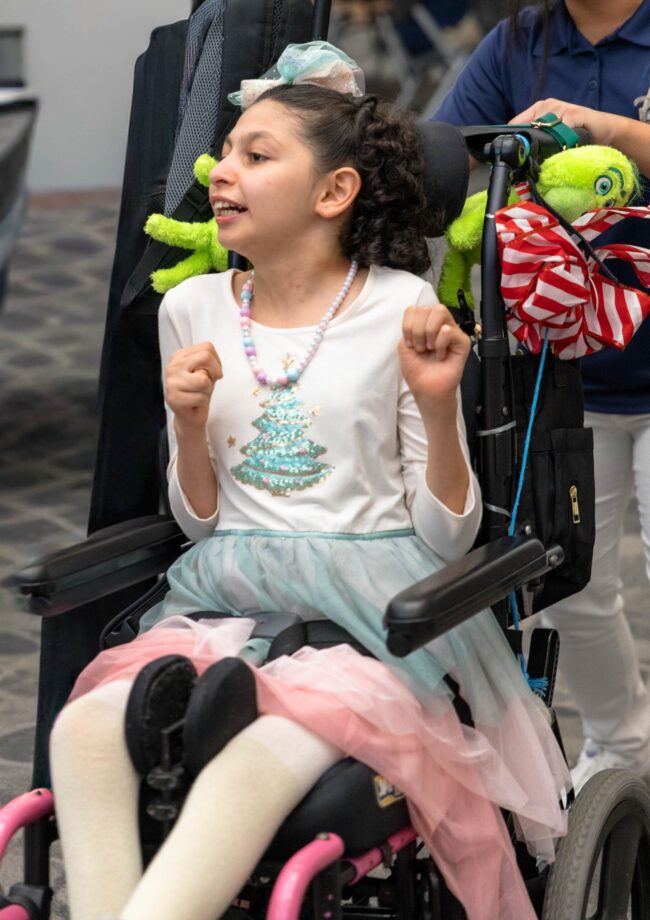 A young guest smiling and holding up a green plush toy